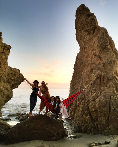group of girls hammocking on the beach between two large rocks