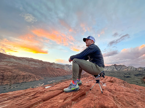 Man sits on compass 360° stool in Snow Canyon Utah enjoying an epic sunset