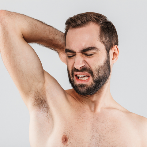 A man who appears to be sniffing his armpit and discovering that the smell is not right.
