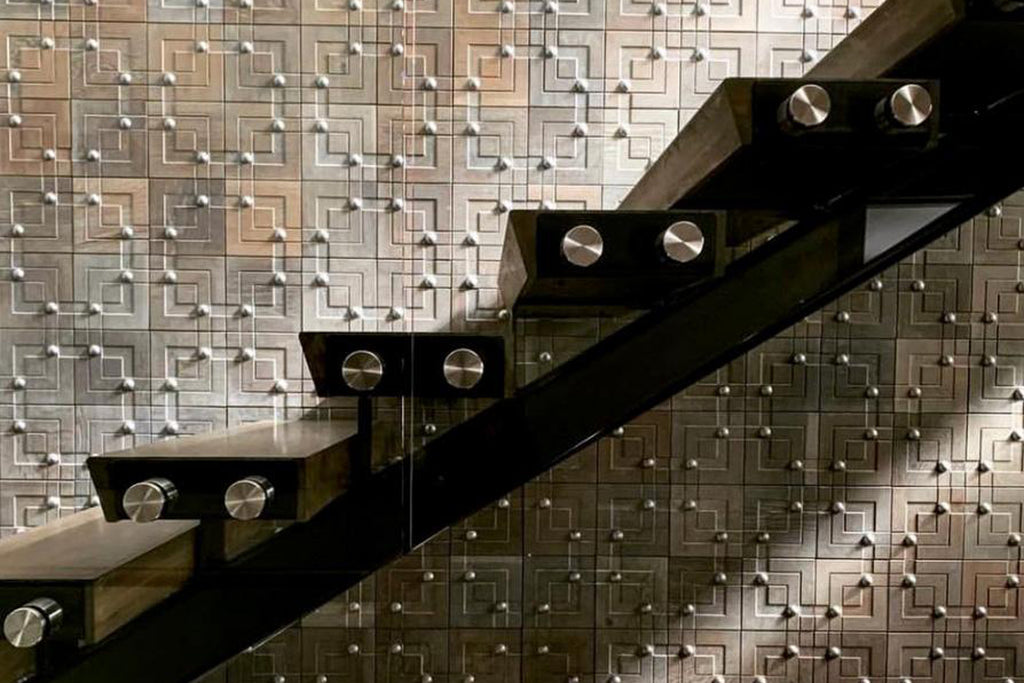 Metal nail heads adorn the sculpted wooden surface in this modern and luxurious staircase