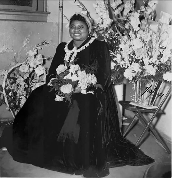 hattie mcdaniel wearing a long velvet gown surrounded by fresh flowers