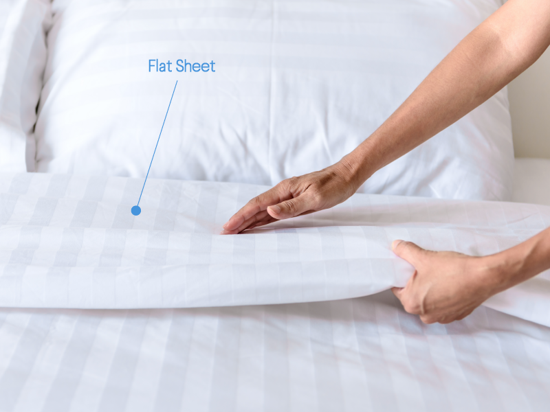Woman putting flat sheet on bed