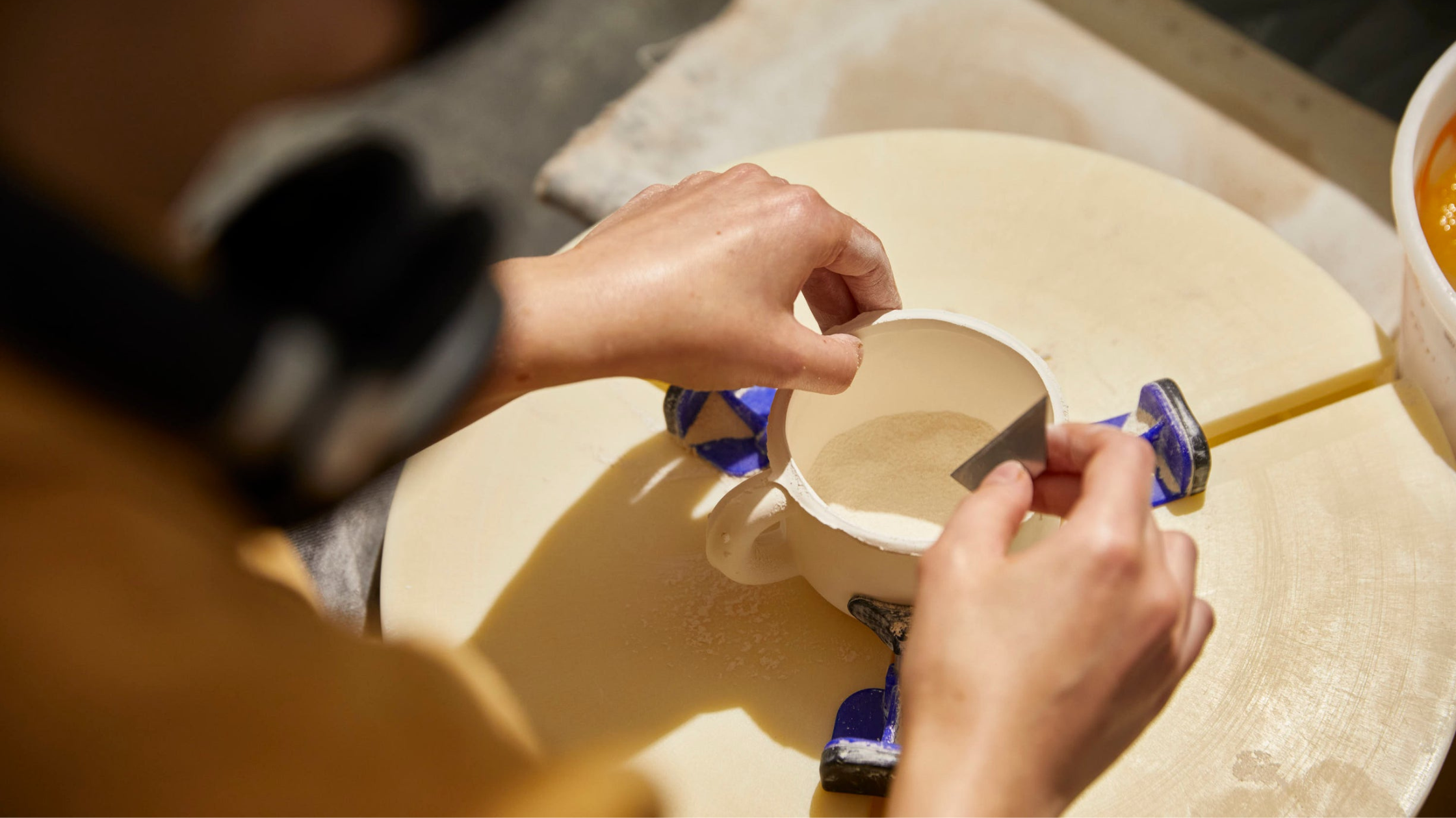 Hands forming a cup on a pottery wheel.