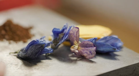 Flower petals of purple and yellow sitting on a ring crafting table