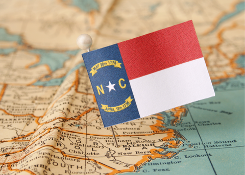 picture of a map with a North Carolina flag pinned on the state of north carolina