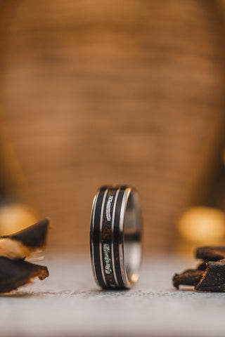 Picture of a custom ring between to scraps of old leather on with a blurry brown background