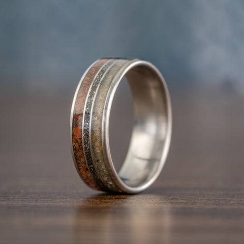 Picture of the Jurassic ring a titanium band that features three inlays of fossilized amber, meteorite dust, and dinosaur bone