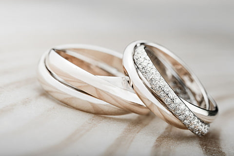 Two stacks of white gold wedding bands with one diamond encrusted band
