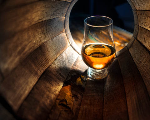 glass of scotch inside of whiskey barrel