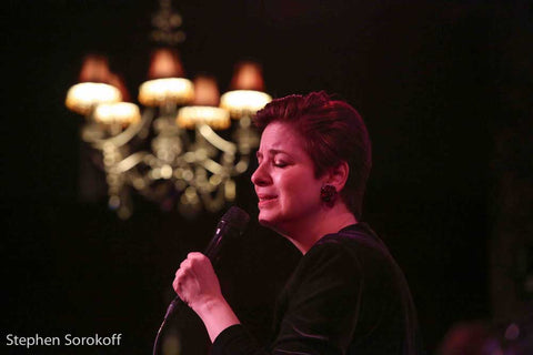 Celia Berk performs in red earrings from Icon Style with a chandelier in the background