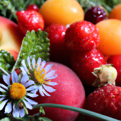 A photograph detail of orchard fruits, an array of berries, and a splash of flowers