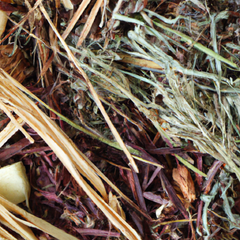 A photograph detail of cedar chips, patchouli leaves, pine needles, sandalwood chips, and vetiver roots