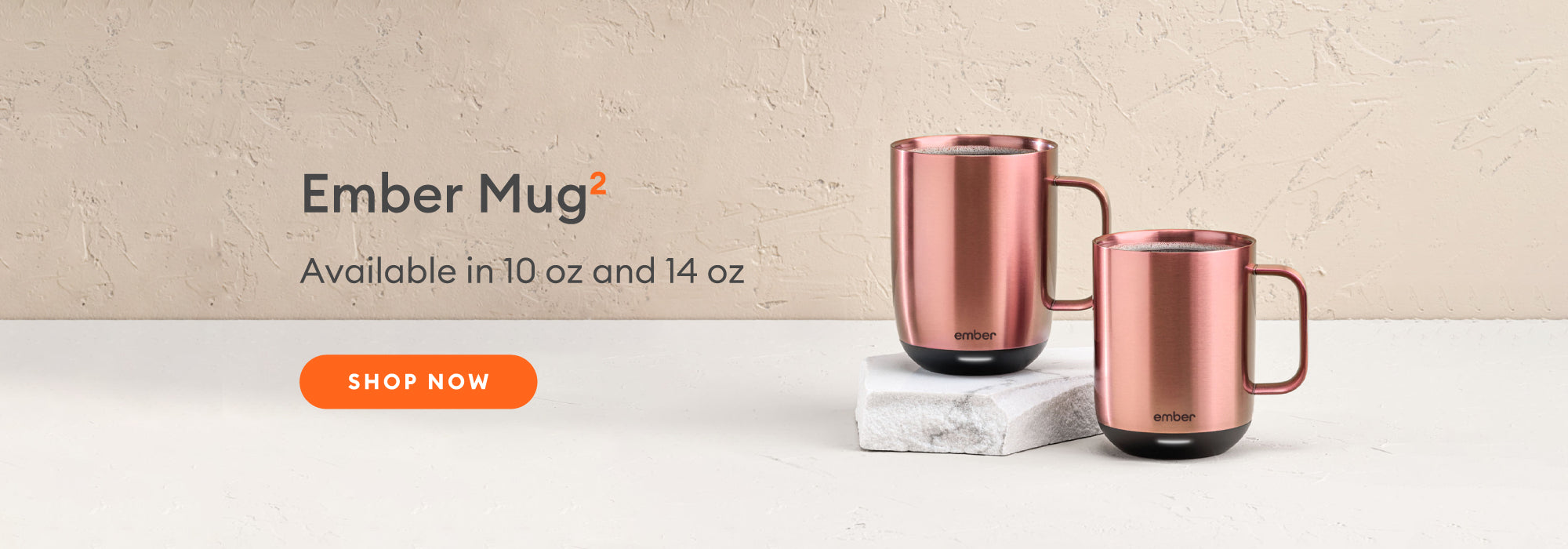 A 10 oz and 14 oz Ember Mug² in Rose Gold sit next to each other on a marble slab.