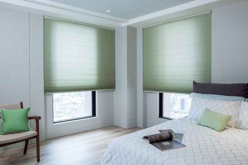 bedroom with two windows with honeycomb blinds filtering the light