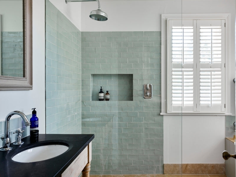 bathroom with shower and shutters on the window