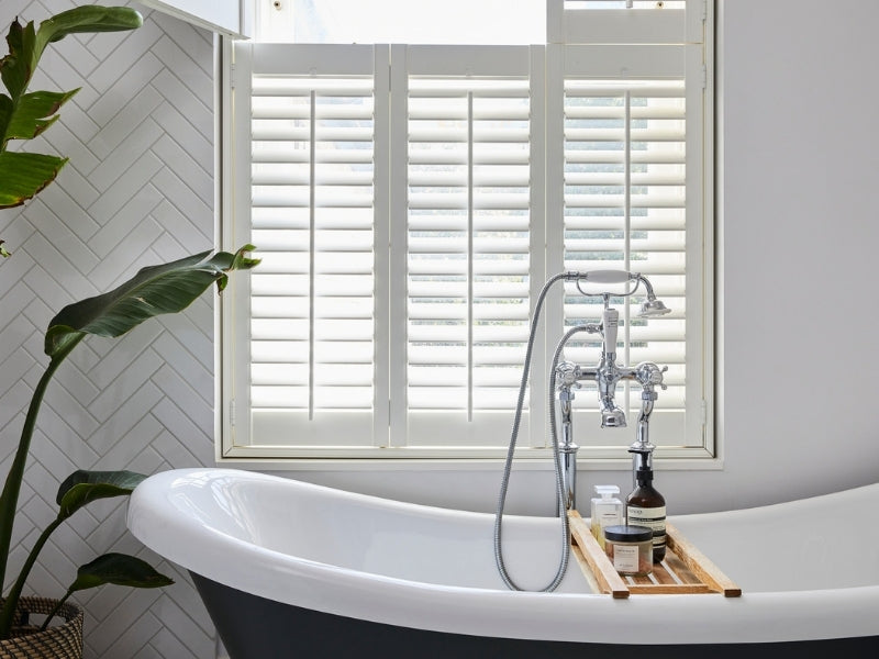 traditional bathtub and shutters on the window