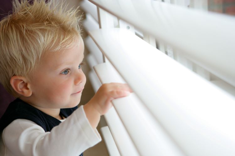 little child looking out a window through open shutters