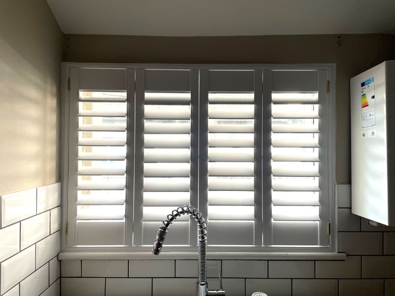 kitchen sink with a window behind and full height shutters