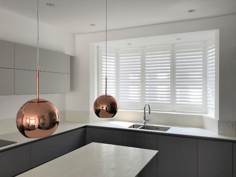 kitchen with ball shaped lights hanging low on the table and plantation shutters on the window