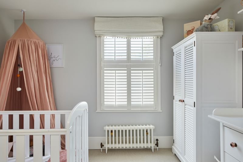 nursery with white furniture and white shutters on the window