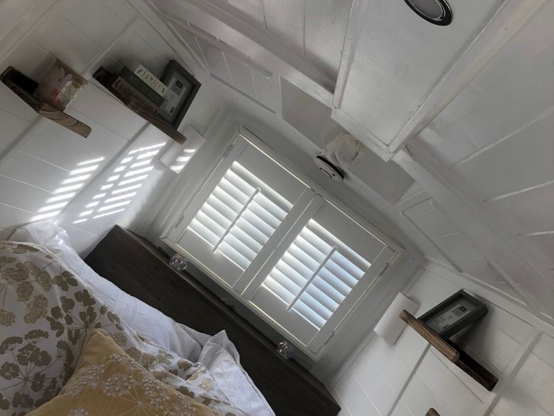 inside a narrowboat with plantation shutters at the end, to provide privacy to the bedroom area