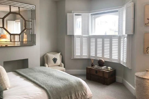 bedroom with bay window and white tier on tier shutters, with upper tier open