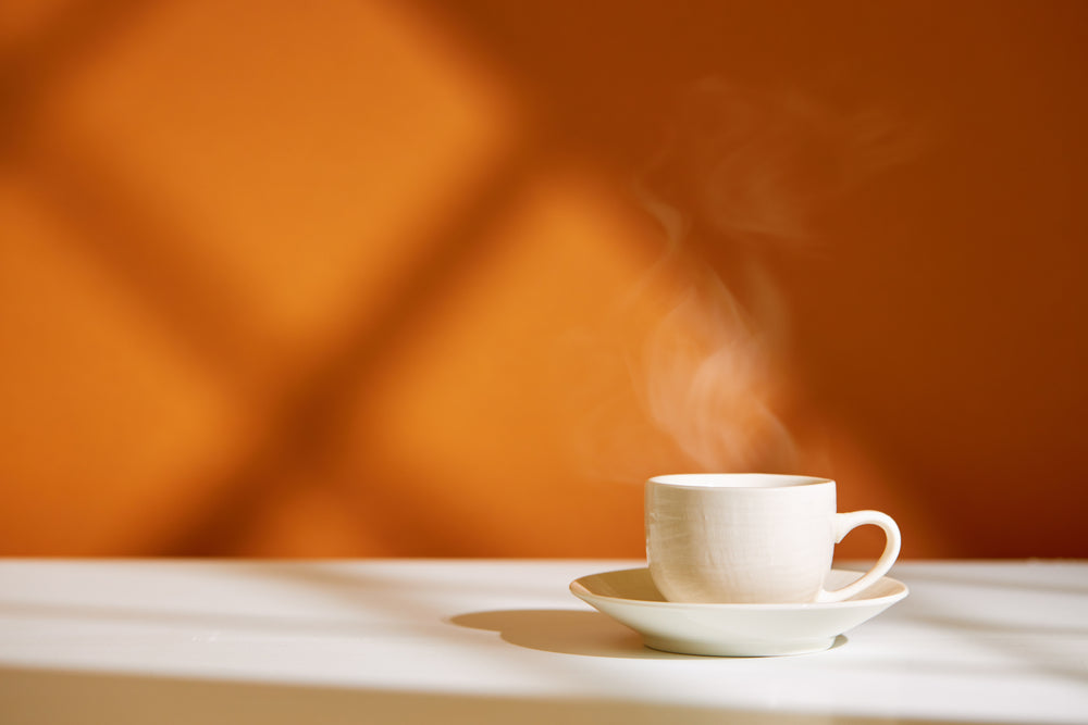 Close-up of coffee cup with steam in white cup on table.