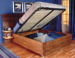 A queen-sized hydraulic bed lifted to show pillows stored underneath.