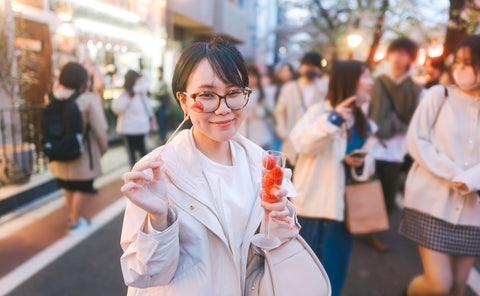 Japan Tokyo city Nakameguro sakura festival famous destination. Young adult asian woman eating strawberry sparkling wine. Japanese people lifestyles at night street sightseeing.
