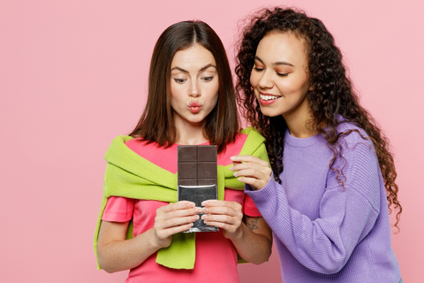 Young female friends sharing chocolate on Valentine's Day