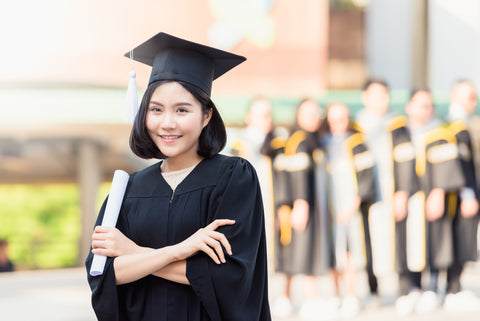 Student girl young woman in cap gown holding diploma scroll in hand.