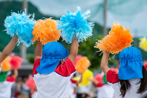 Three children with pom poms on Sports Day in Japan