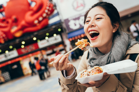 Women eating Takoyaki in the middle of the street, delicious cheap meal