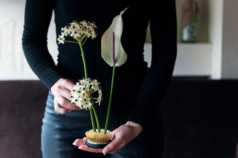 girl holding a minimalist ikebana in a lotus kenzan