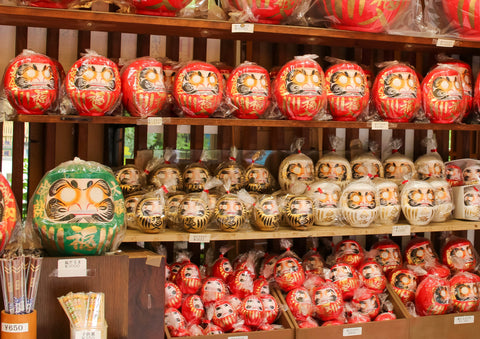 Daruma figures in Rey, white and gold on display in a tourist shop in Tokyo near Jindaiji temple