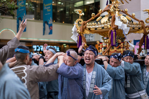 Group of Japanese men carrying heavy mikoshi portable shrines through the streets during Sanja Matsuri Festival