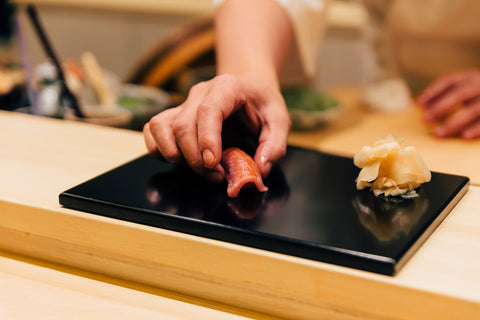 Japanese Omakase meal: Chutoro Sushi (Medium Fatty Bluefin Tuna) served by hand with pickled ginger on glossy black plate. Japanese traditional and luxury meal.