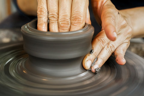 Craftsman molding the clay into the desired shape on potter's wheel. Close-up picture.