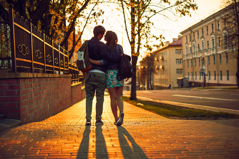 Outdoor lifestyle portrait of young couple in love standing in old town on the street behind sunset