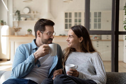 Happy young married couple enjoying cozy romantic weekend time with cup of hot tea coffee chocolate