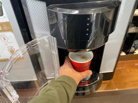 Hand taking the take away paper cup coffee from the coffee machine at Japan Family Mart Convenient store