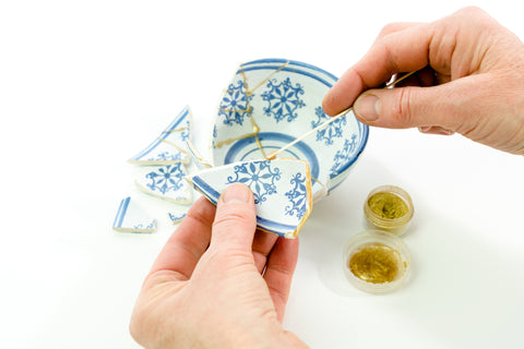 Doing new kintsugi with epoxy glue and gold dust on a broken small porcelain bowl.