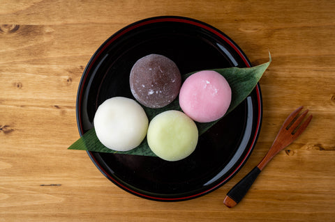 Four pieces of mochi served on a black plate.