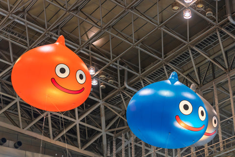 Huge inflatable balloons depicting Slime, the mascot of the Dragon Quest role-playing video game floating under the ceiling of the anime convention