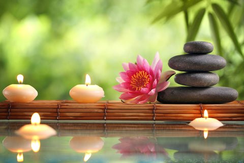 Spa still life with burning candles,zen stone and bamboo mat reflected in a serenity pool