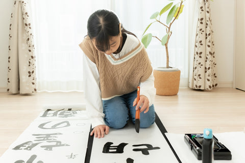 Girl writing Japanese calligraphy