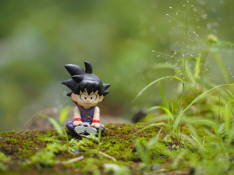 Son Goku character at green land. Blurred view of grass at land. Background is blurred