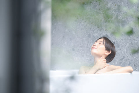A woman relaxing in a bathtub at a ryokan or hotel. For images of hot springs, etc.
