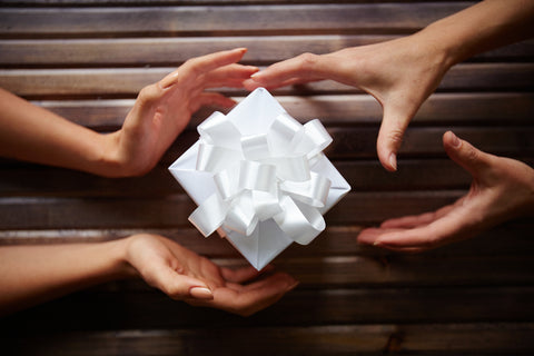 Close-up of gift box among two pairs of hands