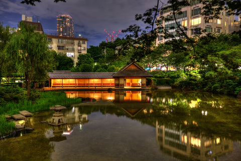 The glow of the Resting House reflects off the pond in Hinokicho Park, a Japanese water garden in Tokyo Midtown, on a summer night